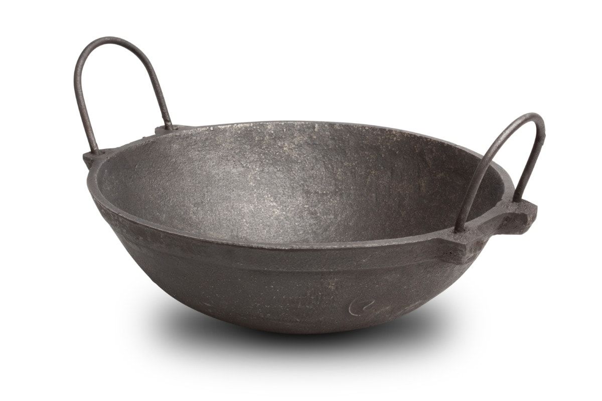 Large cast iron kadai with two handles on a white background