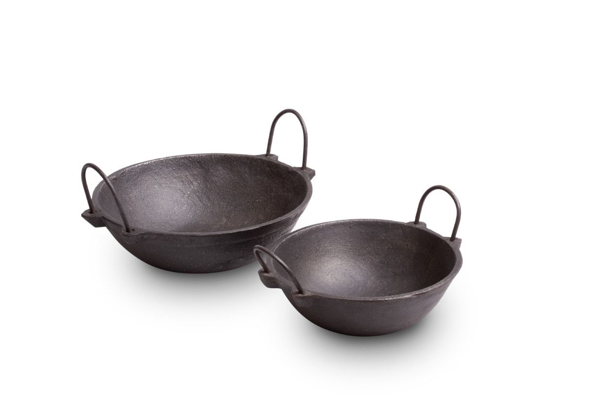 Two cast iron kadais with looped handles on a white background