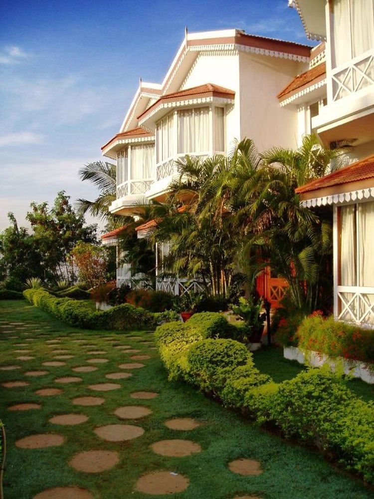 White colonial-style villas with red awnings above a garden path of stepping stones