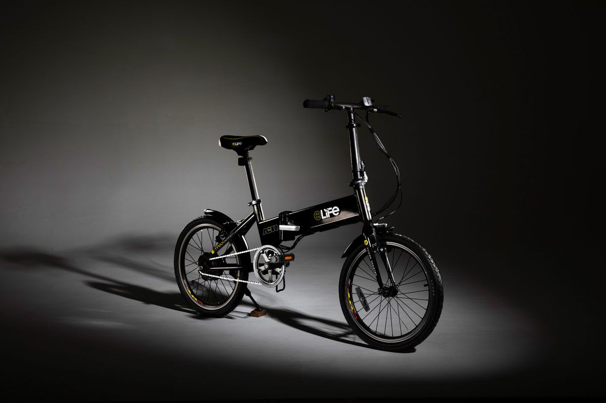Black eLife Air folding bicycle in a spotlight on a dark studio floor