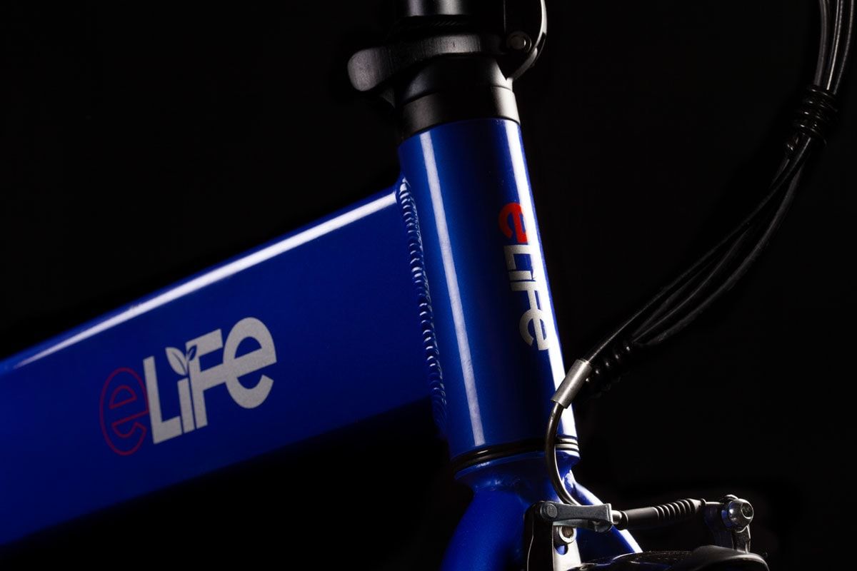 Blue eLife bicycle frame with its logo, lit against black