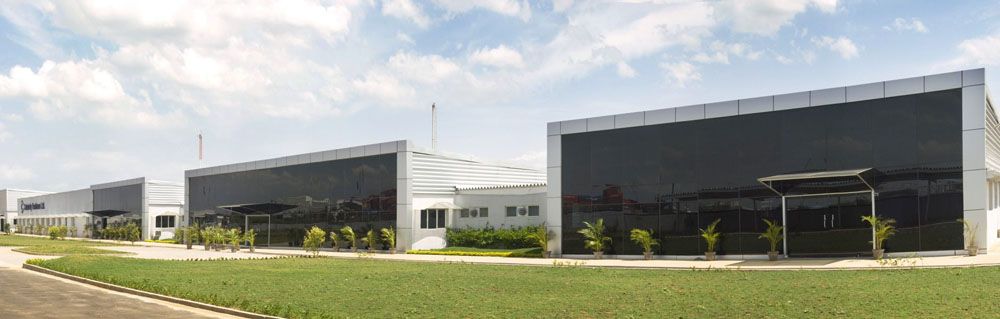 Low modern factory buildings with dark glass facades behind a landscaped lawn