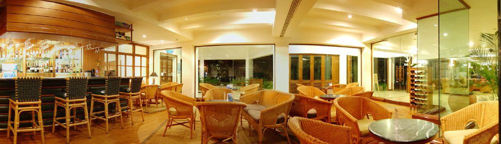 Hotel bar and lounge with cane chairs, high stools and glass walls