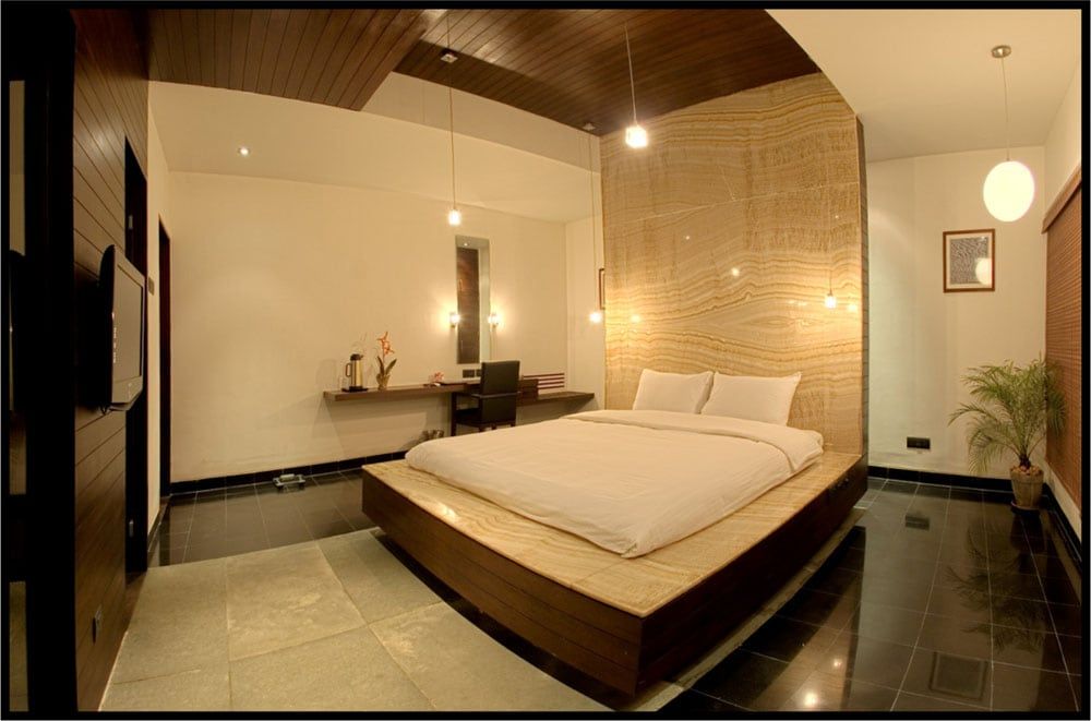 Hotel bedroom with a low platform bed and a backlit onyx feature wall