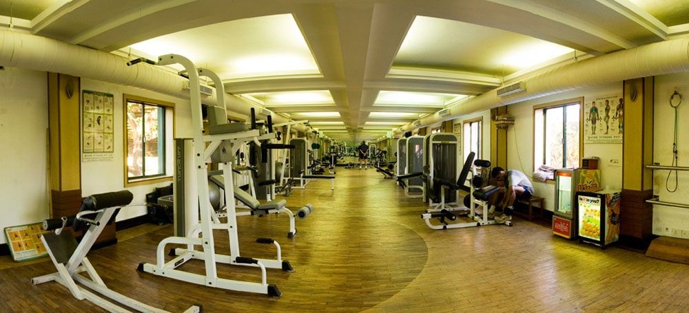 Long hotel gym with weight machines under a vaulted ceiling