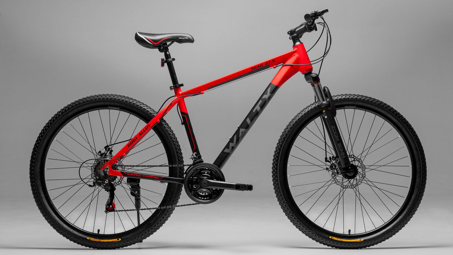 Red and black mountain bike in profile on a grey studio background