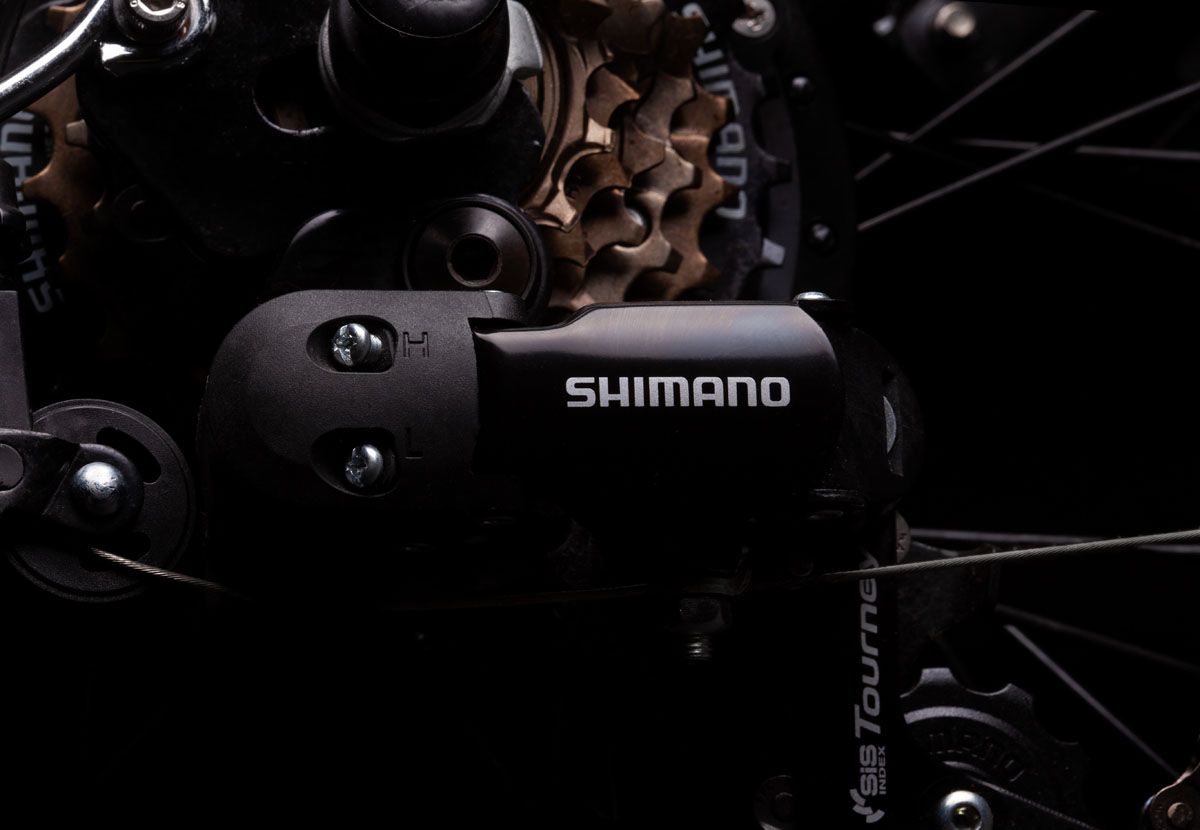 Close-up of a Shimano rear derailleur and gears, against black