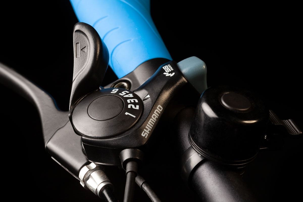 Shimano thumb gear shifter on a bicycle handlebar, against black