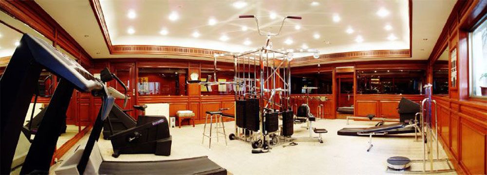 Wood-panelled gym with treadmills and weight machines under a lit ceiling