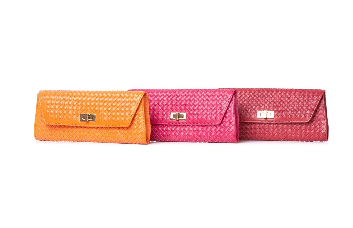 Orange, pink and red woven leather clutches in a row on a white background